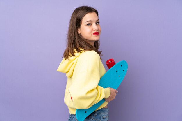 Teenager girl on purple wall with a skate