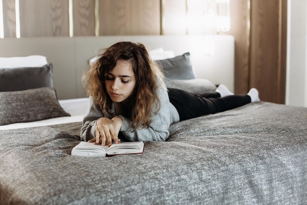 Teenager girl reading book on the bed