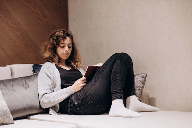 Teenager girl reading book on the couch at home