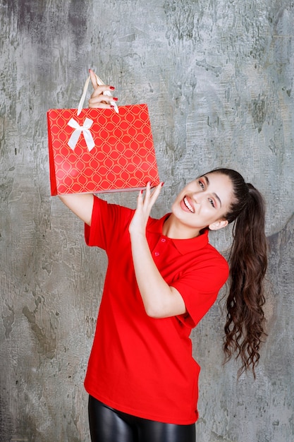 Teenager girl in red shirt holding a red shopping bag