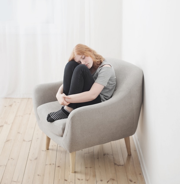 Teenager girl sitting in gray armchair