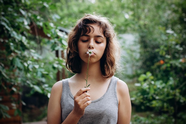 写真 森の中でカモミールの花を嗅ぐティーンエイジャーの女の子。自然の美。率直な瞬間