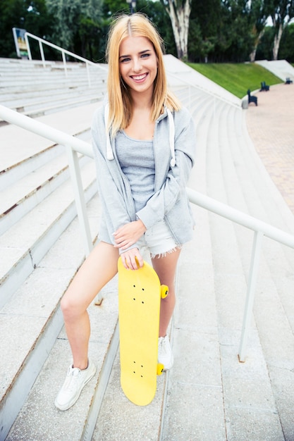 Teenager girl standing on stairs with skateboard