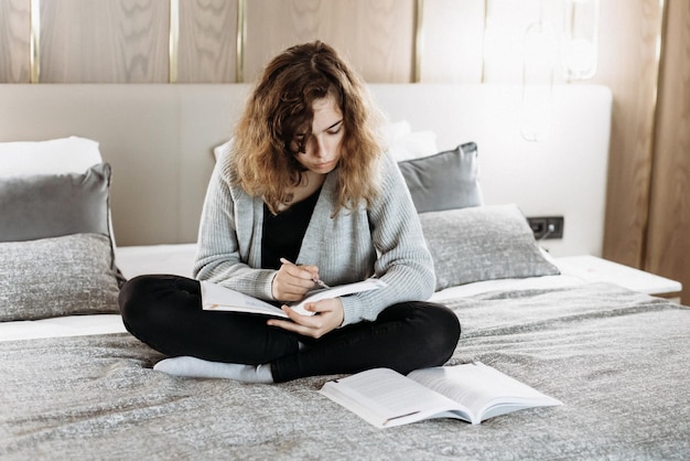 Ragazza adolescente che studia sul letto a casa. studente che fa i compiti