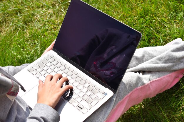 ラップトップで勉強しているティーンエイジャーの女の子遠隔教育コンピューターで公園で幸せな女子高生