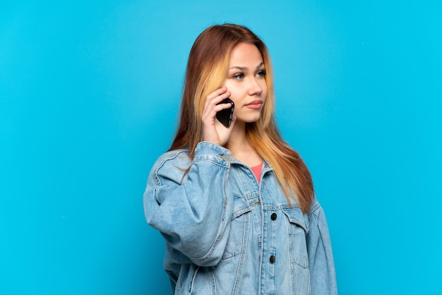 Teenager girl using mobile phone over isolated background looking to the side