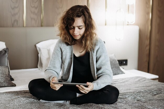 Teenager girl watching video or reading book on tablet on the
bed