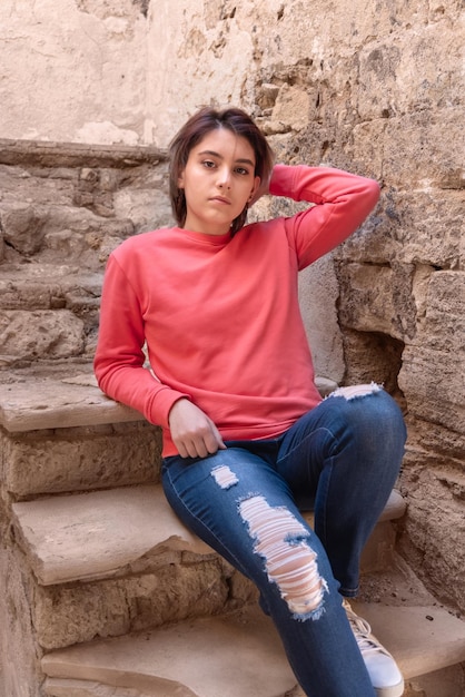 Foto ragazza adolescente che indossa una camicia rosa a maniche lunghe seduta mockup all'aperto