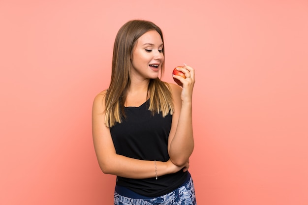 Teenager girl with an apple over isolated wall