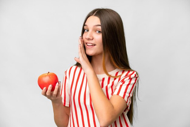 Teenager girl with an apple over isolated white background whispering something