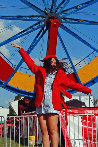 Teenager girl with arms outstretched jumping against ferris wheel