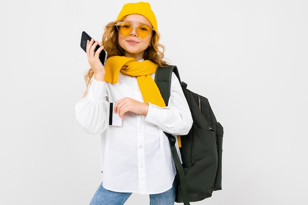 Teenager girl with a backpack behind her talking on the phone on a white isolated background.