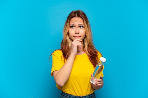 Teenager girl with a bottle of water isolated having doubts and thinking