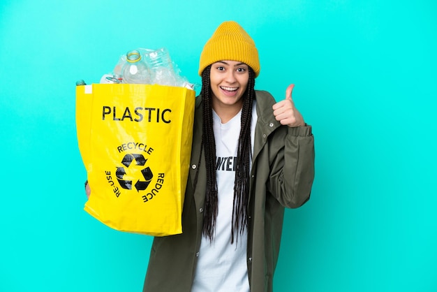 Teenager girl with braids holding a bag to recycle giving a thumbs up gesture