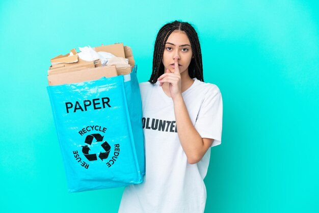 Teenager girl with braids holding a bag to recycle showing a sign of silence gesture putting finger in mouth