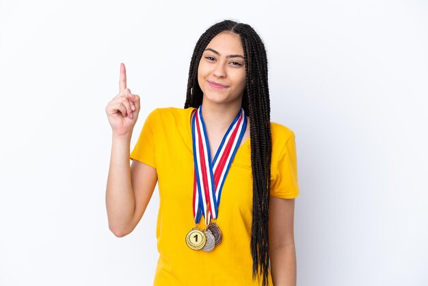 Teenager girl with braids and medals over isolated pink background pointing with the index finger a great idea