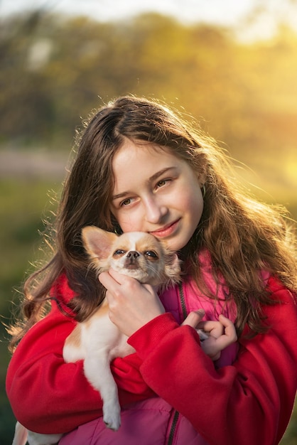 Una ragazza adolescente con un cane chihuahua sullo sfondo della natura in una giornata di sole. umano e animale domestico