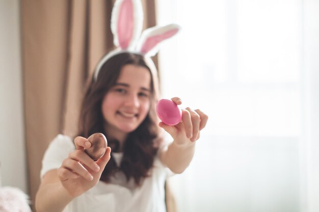 Teenager girl with Easter ears and a wicker Easter basket on a bed in a living room