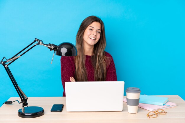 Teenager girl with a laptop in a table laughing