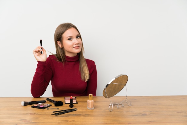 Teenager girl with makeup palette and cosmetics in a table