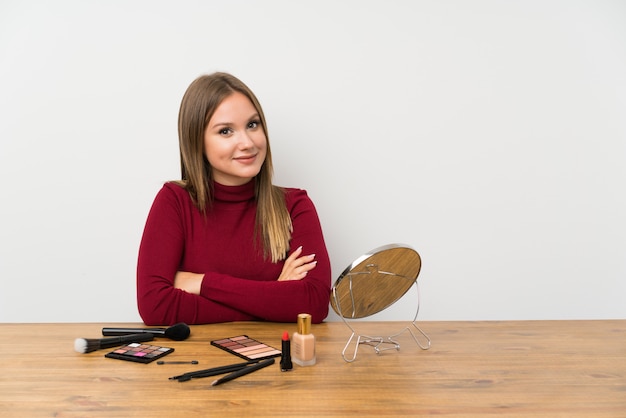 Teenager girl with makeup palette and cosmetics