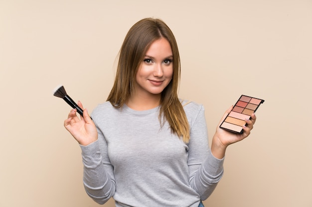 Teenager girl with makeup palette over isolated background