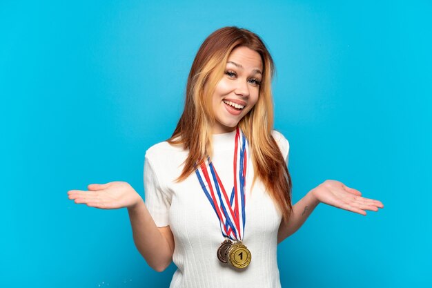 Photo teenager girl with medals over isolated background with shocked facial expression