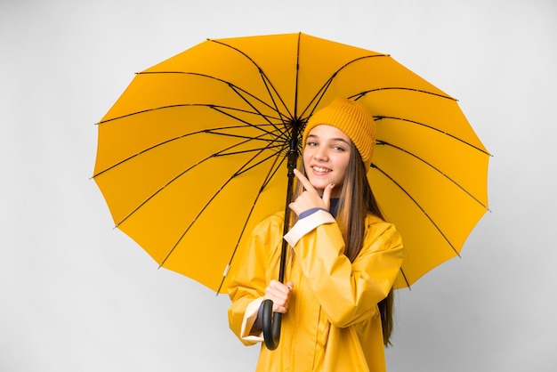 防雨コートと分離の白い背景の上の傘幸せと笑顔のティーンエイ ジャーの女の子