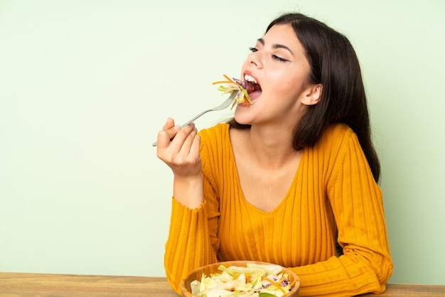 Foto ragazza dell'adolescente con insalata sopra la parete verde