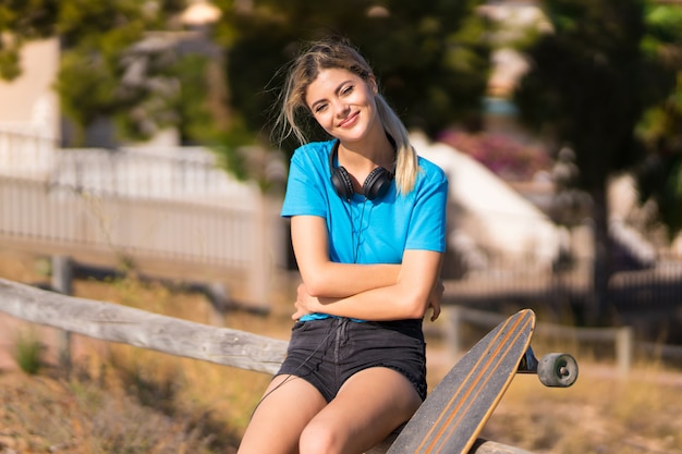 Teenager girl with skate at outdoors with arms crossed and looking forward