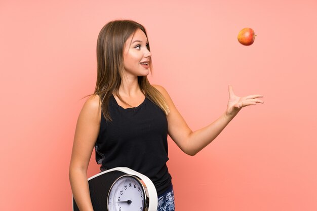 Photo teenager girl with weighing machine over isolated wall