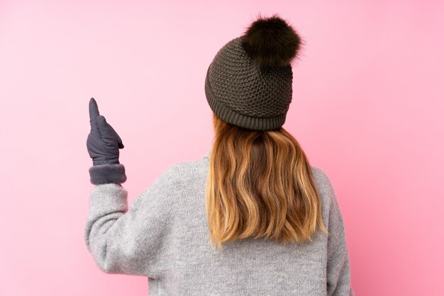 Teenager girl with winter hat over isolated pink wall