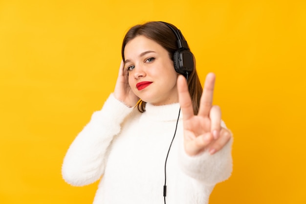 Teenager girl on yellow listening music and singing