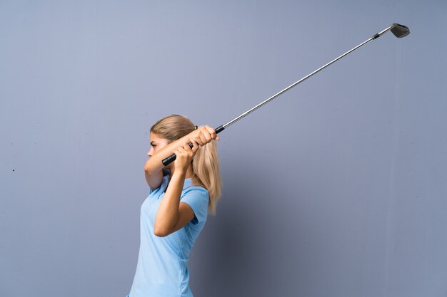 Teenager golfer girl over grey wall