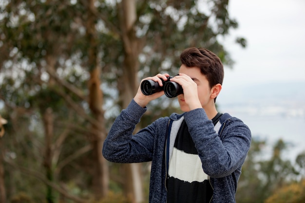 Teenager guy looking with binoculars 