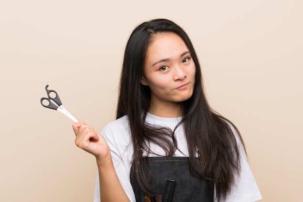 Teenager hairdresser girl over isolated wall