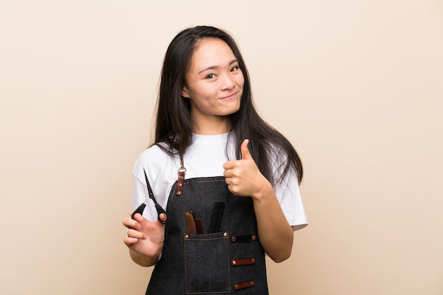 Teenager hairdresser girl with thumbs up because something good has happened