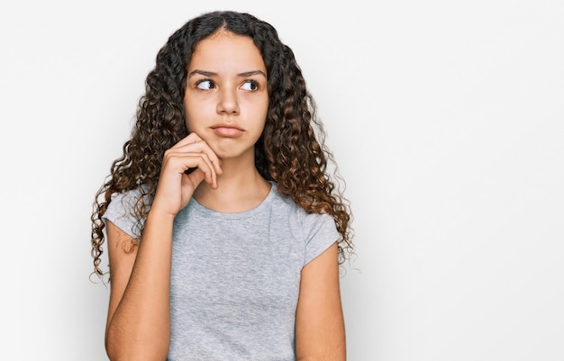 Foto adolescente ragazza ispanica che indossa abiti casual faccia seria pensando alla domanda con la mano sul mento, premurosa sull'idea confusa