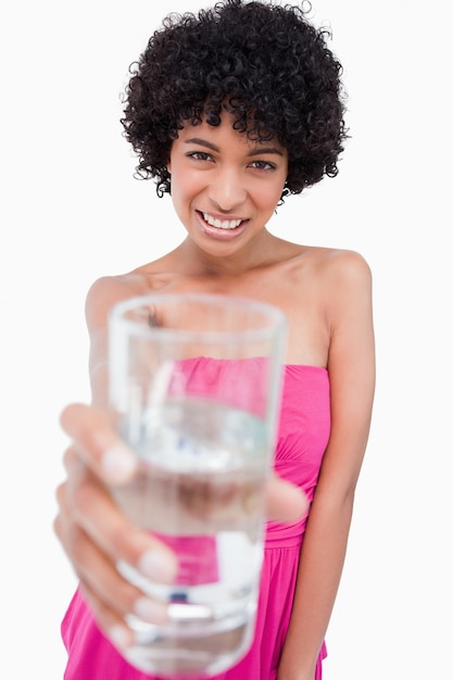 Teenager holding a glass of water in front of her while smiling