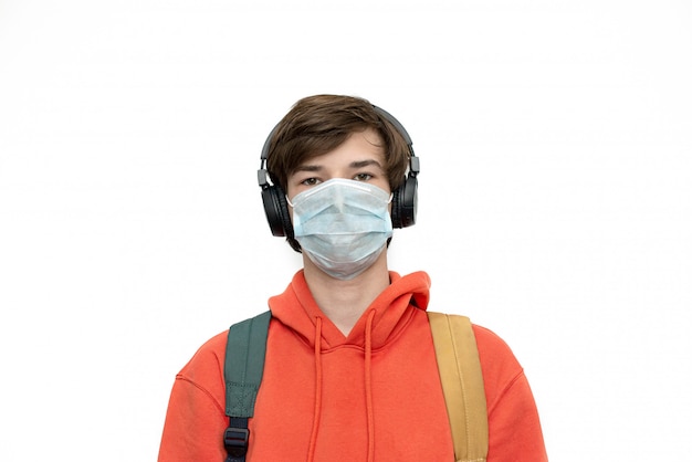 Teenager at home schooling in a medical mask and with a backpack isolated during coronovirus.