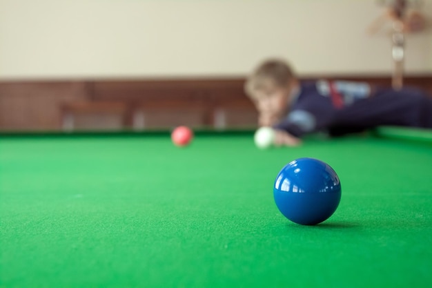 Teenager is playing snooker Red balls are in the foreground