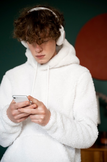 Photo teenager listening to music using his smartphone while being at home