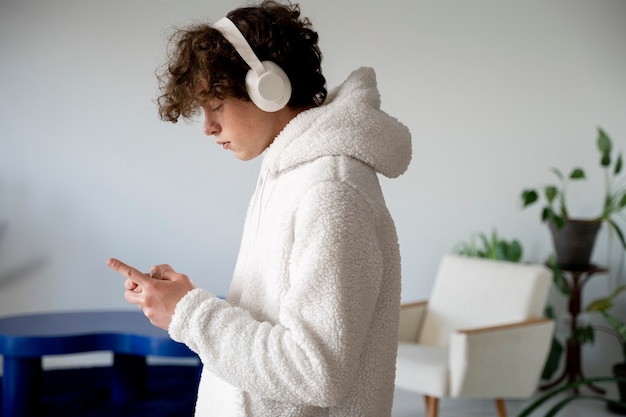 Photo teenager listening to music using his smartphone while being at home