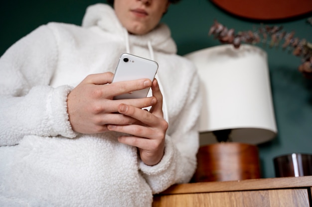 Foto adolescente che guarda il suo smartphone mentre è a casa