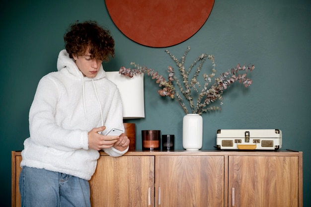 Photo teenager looking at his smartphone while being at home