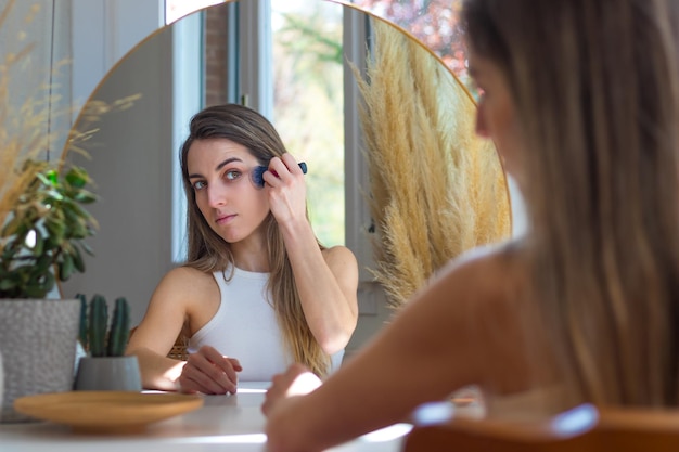 Подросток смотрит в зеркало и учится делать макияж в первый раз