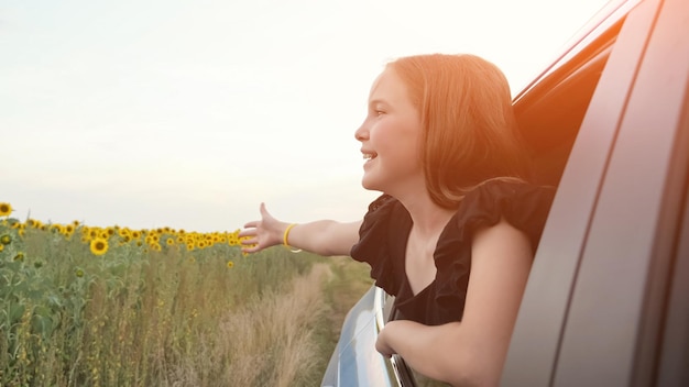 10 代の若者がひまわりの景色を眺めながら車の窓の外を見る