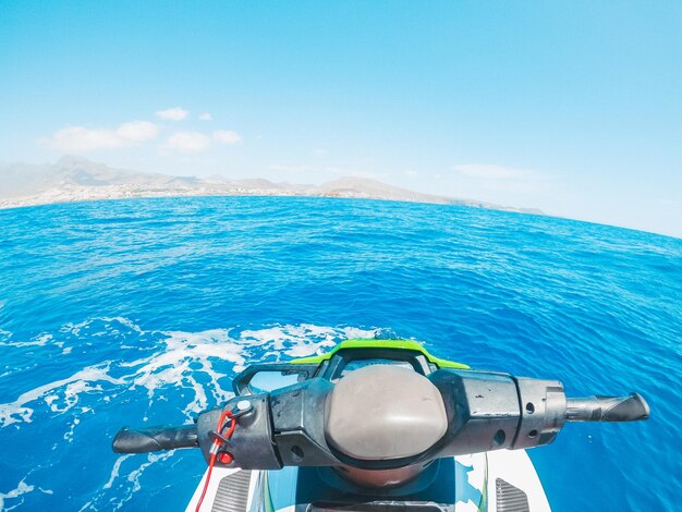 Foto uomo adolescente che si gode l'estate in una moto d'acqua in mezzo al mare divertendosi a correre da solo e isolato