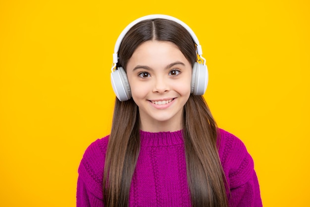 Teenager in modern wireless headphones enjoying song music in audio app listening to her favorite music over yellow studio background