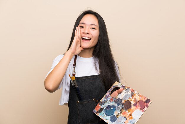 Teenager painter asian girl shouting with mouth wide open